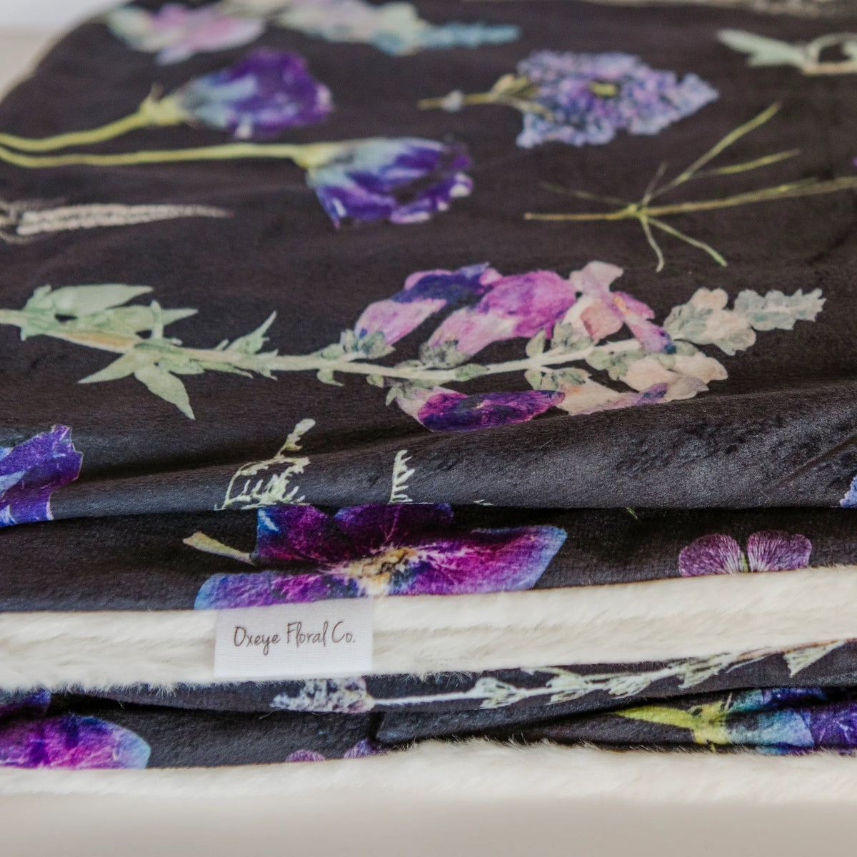 Folded throw blanket with floral pattern on a dark background