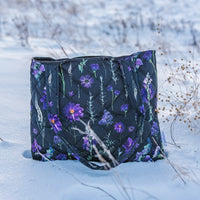 Black quilted tote with purple pressed flower design sitting in the snow