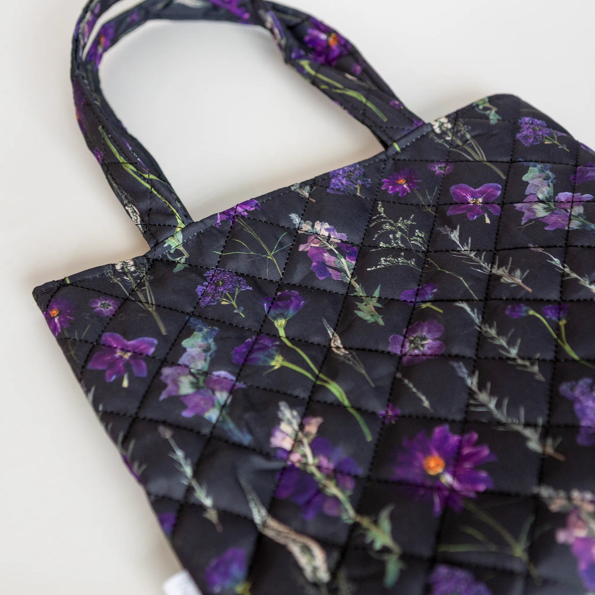 Closeup of a black and purple pressed flower tote with quilted fabric