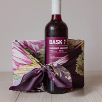 Gift wrapped in pretty floral reusable fabric wrap with a bottle of red wine